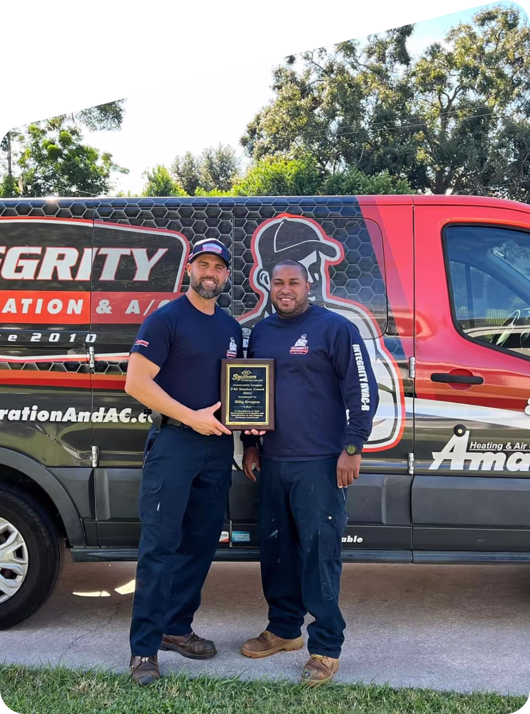Integrity technicians holding an award in front of their branded service van