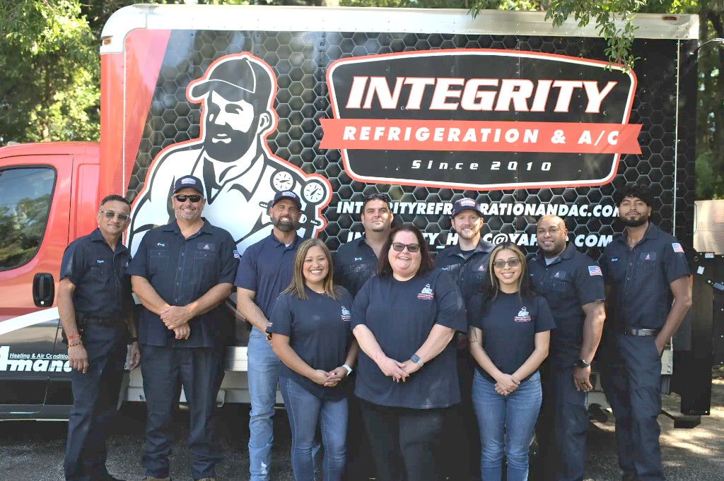 Team of HVAC professionals from Integrity Refrigeration & AC posing in front of their branded service van