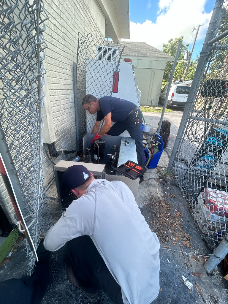 Integrity technicians servicing an outdoor HVAC unit on a job site