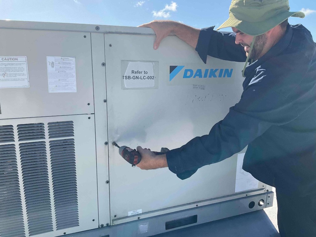 Integrity Refrigeration & AC technician servicing a rooftop Daikin HVAC unit